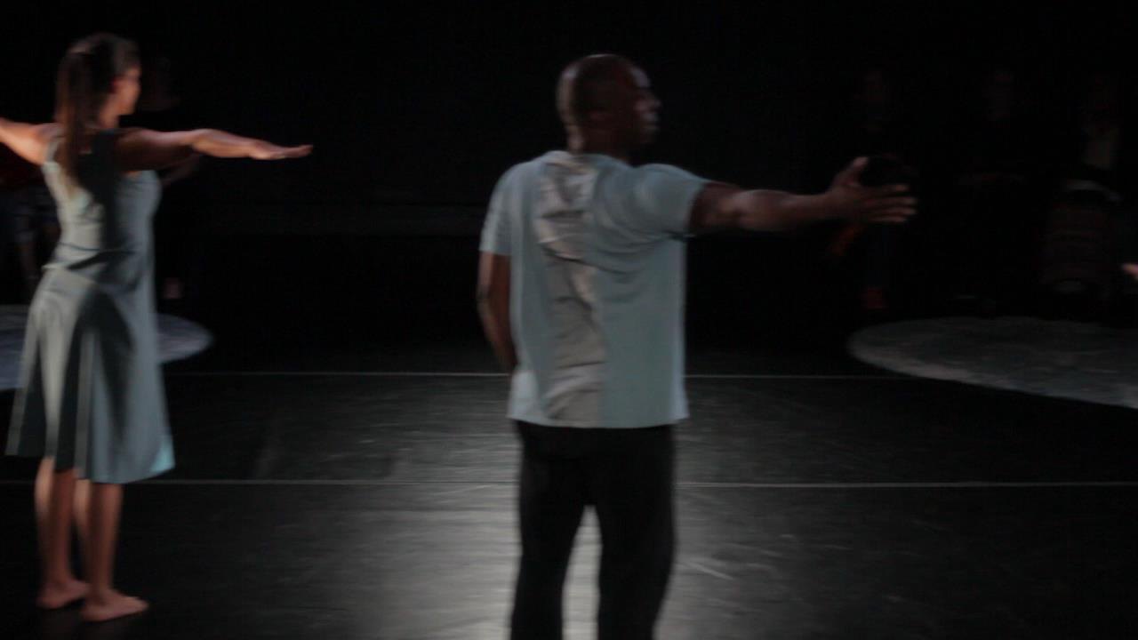 Boris Willis and another dancer reaching outward on a dim stage