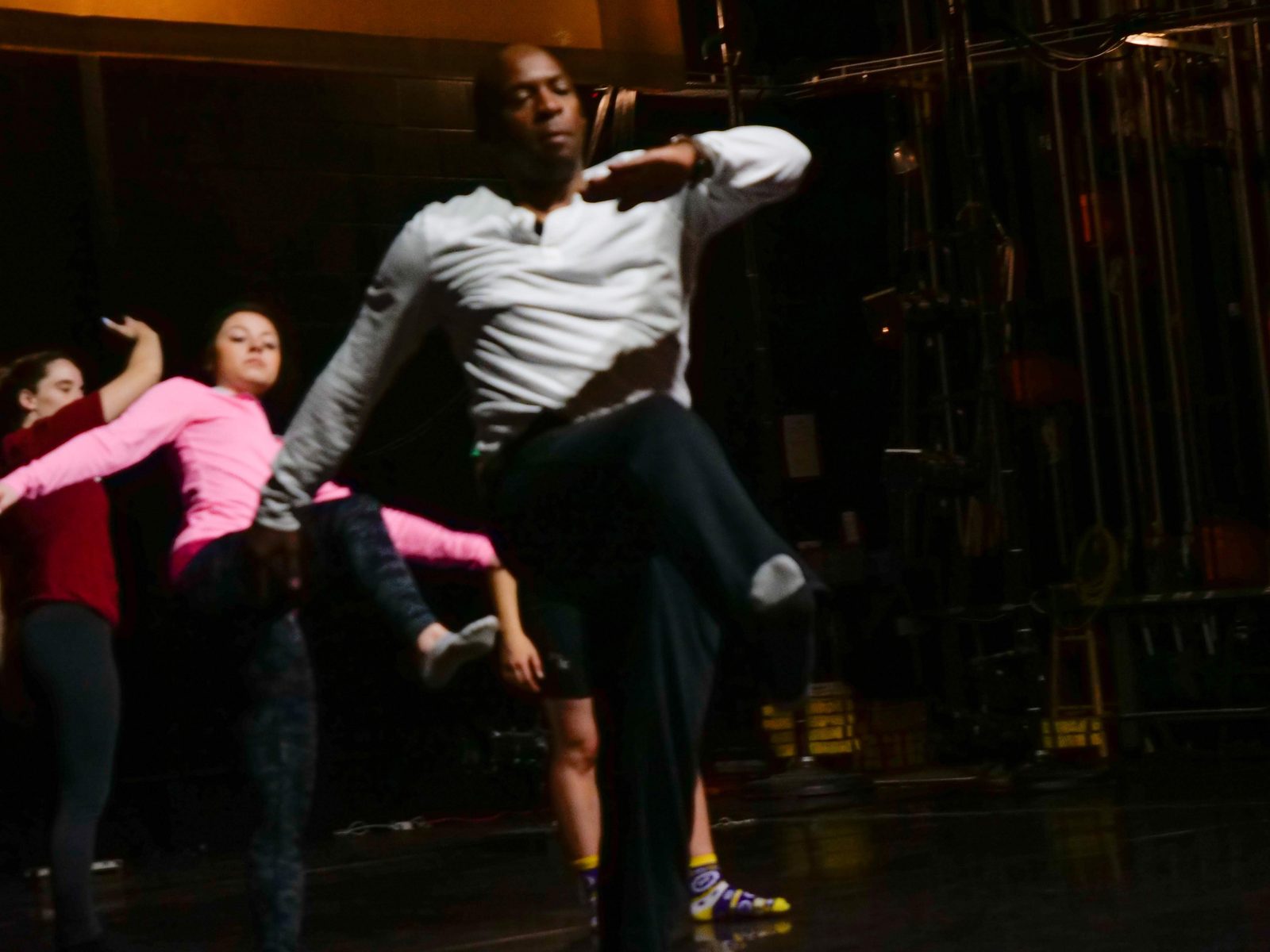 Boris Willis with one knee lifted, dancers extending their arms in the background