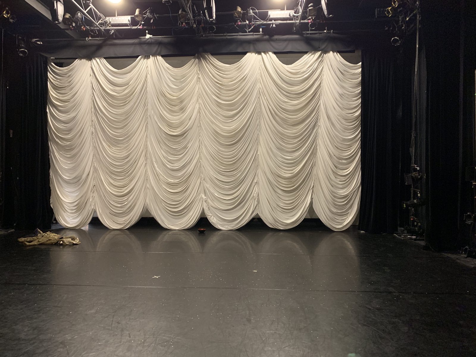 An empty stage framed by tall theatrical drapes